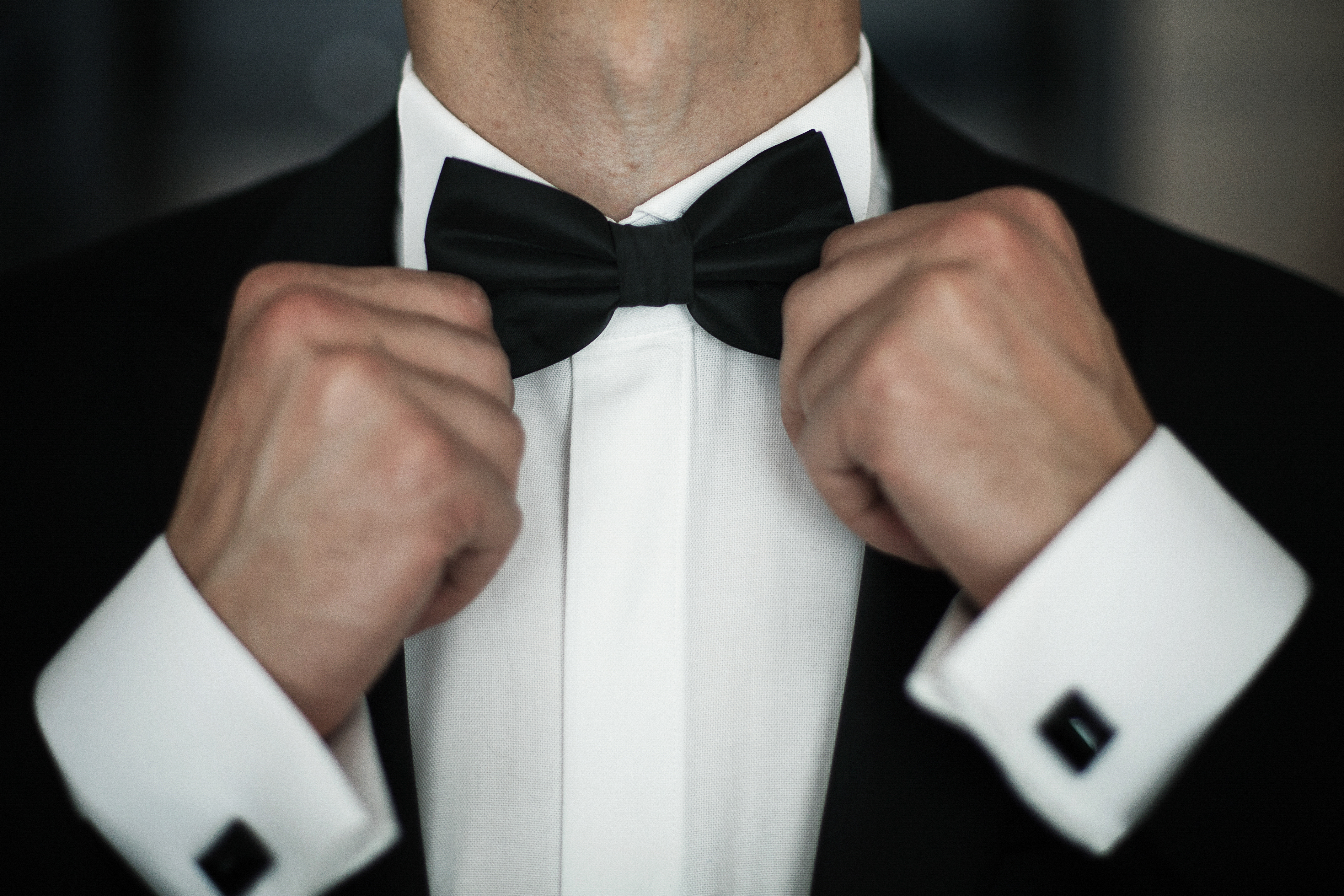 Man fies black bow tie on white shirt